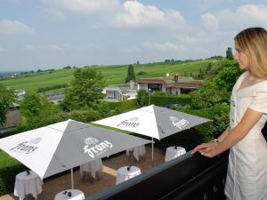 una donna in piedi su un balcone con due ombrelloni di Das Haus am See a Sinzheim