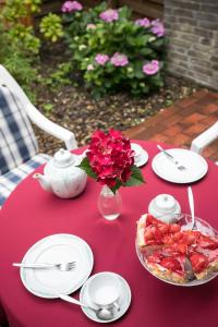 a red table with plates and a vase of red flowers at Ferienhaus an der Baeke E in Bad Zwischenahn