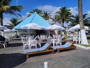 a group of chairs and umbrellas on a beach at Kitnets a 200 m da praia in Peruíbe