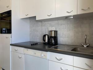 a kitchen with white cabinets and a sink at 533 - Appartement T1 situé à quelques pas de la grande plage d'Erquy et du centre in Erquy