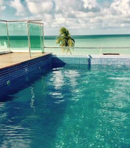 una piscina con una palmera y el océano en Relais de Charme Boutique Hotel Pititinga, en Rio do Fogo