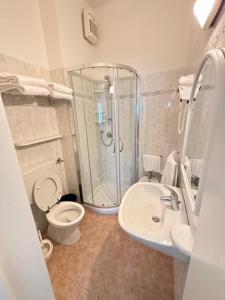 een badkamer met een douche, een toilet en een wastafel bij Hotel Fiorenza in Milano Marittima
