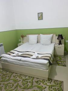 Cama en habitación con pared verde en Lind Hotel and Guest House, en Gyumri
