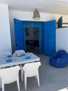 einen Tisch und Stühle in einem Zimmer mit blauen Türen in der Unterkunft Villa dar nina hergla in Harqalah