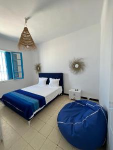 ein Schlafzimmer mit einem großen Bett und einem großen blauen Ottomanen in der Unterkunft Villa dar nina hergla in Harqalah
