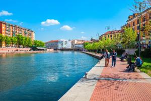 a group of people standing on a sidewalk next to a river at Stylish Navigli Apartment - Walk to Darsena & Duomo in Milan
