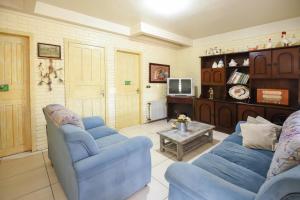 a living room with two blue chairs and a tv at Hotel Pequenino in Canela