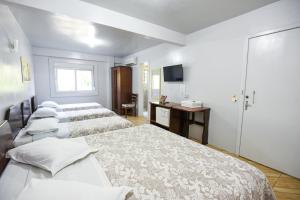 a hotel room with three beds and a television at Hotel Pequenino in Canela