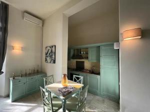 kuchnia z zielonymi szafkami oraz stołem i krzesłami w obiekcie Principi di Piemonte con Piscina w mieście Tirrenia