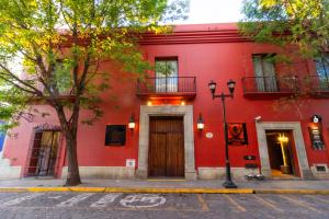 a red building with a wooden door on a street at Hotel Boutique Naura Centro in Oaxaca City
