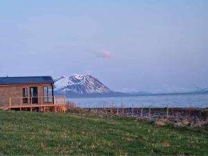 a house with a snow covered mountain in the background at Cozy cabin with amazing sauna house in Straumen