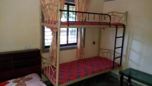 a bedroom with two bunk beds and a window at Govindaashram in Bhogwe