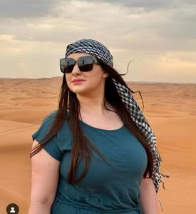 a woman wearing sunglasses and a hat in the desert at Journey Desert Camp Jaisalmer in Jaisalmer