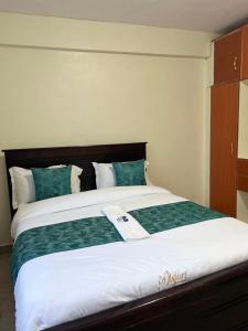 a bedroom with a large bed with green and white sheets at The comfortplace oak 102 in Kericho