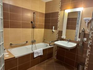 a bathroom with a tub and a sink and a shower at Apartment 416 with mountain view in Hotel Crocus, Strbske Pleso in Štrbské Pleso