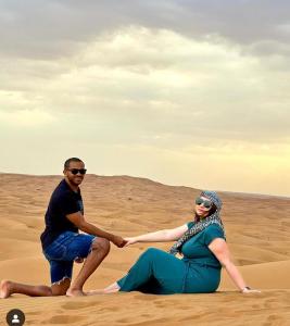 a man and a woman sitting in the desert at Journey Desert Camp Jaisalmer in Jaisalmer