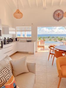 een keuken en een woonkamer met een bank en een tafel bij Résidence Les Raisins Clairs - Villas standing 4 étoiles , vue sur mer panoramique & piscine à débordement in Saint-François