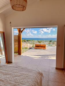 a bedroom with a view of the ocean from a balcony at Résidence Les Raisins Clairs - Villas standing 4 étoiles , vue sur mer panoramique & piscine à débordement in Saint-François