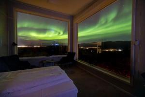 a bedroom with a bed and a window with the aurora at Aurora Borealis Observatory in Silsand