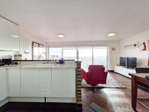 a kitchen with white cabinets and a red chair at Sea Scene's , Hayling Island in South Hayling