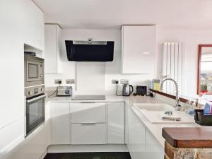 a white kitchen with white cabinets and a sink at Sea Scene's , Hayling Island in South Hayling
