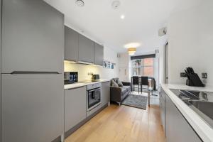 uma cozinha com armários brancos e uma sala de estar em Modern 1 Bed Apartment Camden em Londres