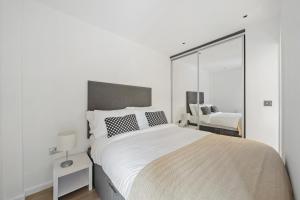 um quarto branco com uma cama grande e uma cadeira em Modern 1 Bed Apartment Camden em Londres