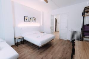 a white bedroom with two beds and a wooden floor at Clink Rooms & Flats in Valencia