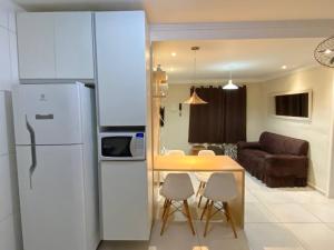 a kitchen with a white refrigerator and a table with chairs at Apto novo pertinho da praia em Boracéia, Bertioga in Bertioga