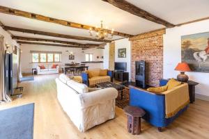 a living room with couches and a brick wall at The Granary - Wood Farm Barn. Luxury Barn with wonderful countryside views in Bawdeswell