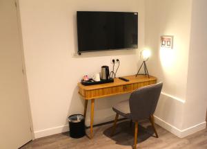 a desk with a chair and a television on a wall at Avia H&ocirc;tel Saphir Montparnasse in Paris