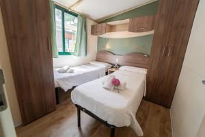 Habitación con 2 camas y sábanas blancas. en Weekend Glamping Resort, en San Felice del Benaco