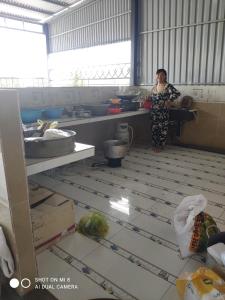 une femme debout dans une cuisine préparant la nourriture dans l'établissement Nhà nghỉ Hoa Dũng, à Hà Tiên
