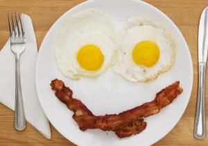 two fried eggs and bacon on a white plate at Hotel s.n.a. grand in Lucknow