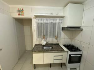 a small kitchen with a sink and a stove at Apto novo pertinho da praia em Boracéia, Bertioga in Bertioga