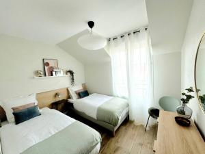 ein Schlafzimmer mit zwei Betten und einem Tisch und einem Spiegel in der Unterkunft New Disneyland Paris Serena Apartment in Bussy-Saint-Georges