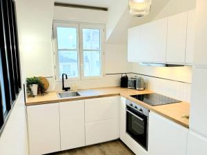 cocina con armarios blancos, fregadero y ventana en New Disneyland Paris Serena Apartment en Bussy-Saint-Georges