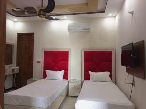 duas camas num quarto com cabeceiras vermelhas em Dove Inn Family Residency Johar Town em Lahore
