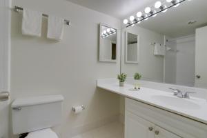Baño blanco con lavabo y espejo en Airport Proximity Condo at Crystal City, en Arlington