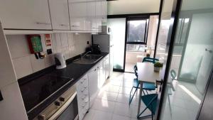 a kitchen with white cabinets and a sink and a table at Guesthouse Metro Station in Matosinhos