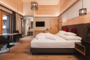 a bedroom with a large white bed and a table at Hundehotel Riederhof in Ried im Oberinntal