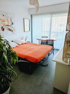 ein Schlafzimmer mit einem Bett mit einer orangefarbenen Decke in der Unterkunft Rivage de Rêve - Hyères Plage in Hyères