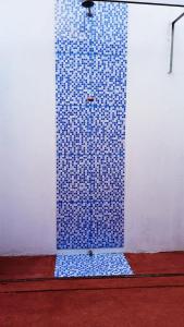 una doccia piastrellata blu su una parete bianca di Casa MD a Camocim