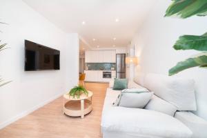 a living room with a white couch and a tv at Soler Apartments in Sant Adria de Besos