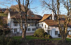 une grande maison blanche avec des arbres au premier plan dans l'établissement Domaine du Deven Grandvaux, à Grandvaux