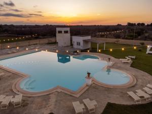 eine Aussicht über einen Pool mit Stühlen und Sonnenuntergang in der Unterkunft Masseria Rauccio in Torre dell'Orso