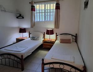 two beds in a room with two lamps on tables at The White House in Calliaqua