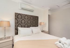 a bedroom with a large white bed with two lamps at Sandringham 45 in Cape Town