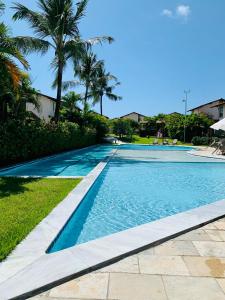 a swimming pool with blue water and palm trees at Bangalô Boutique com piscina Privativa in Porto De Galinhas
