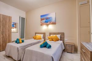 two beds in a hotel room with yellow and blue pillows at Aloha - Village Apartment 2 BR in Mellieha in Mellieħa